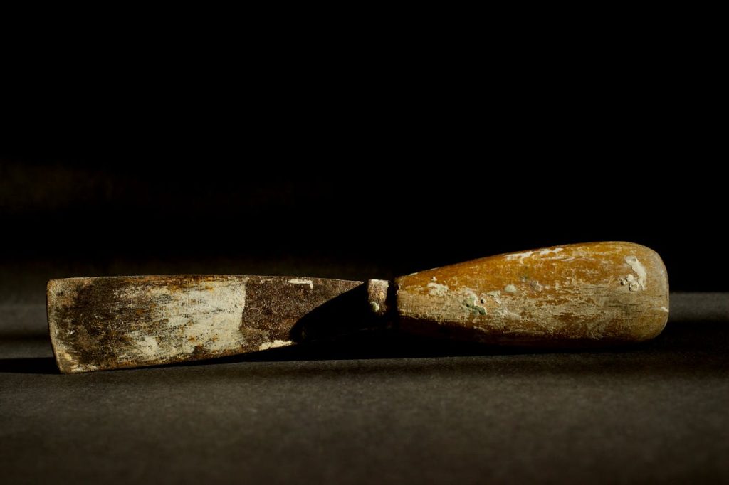 A close-up view of a vintage chisel with a wooden handle, showcasing its worn texture.